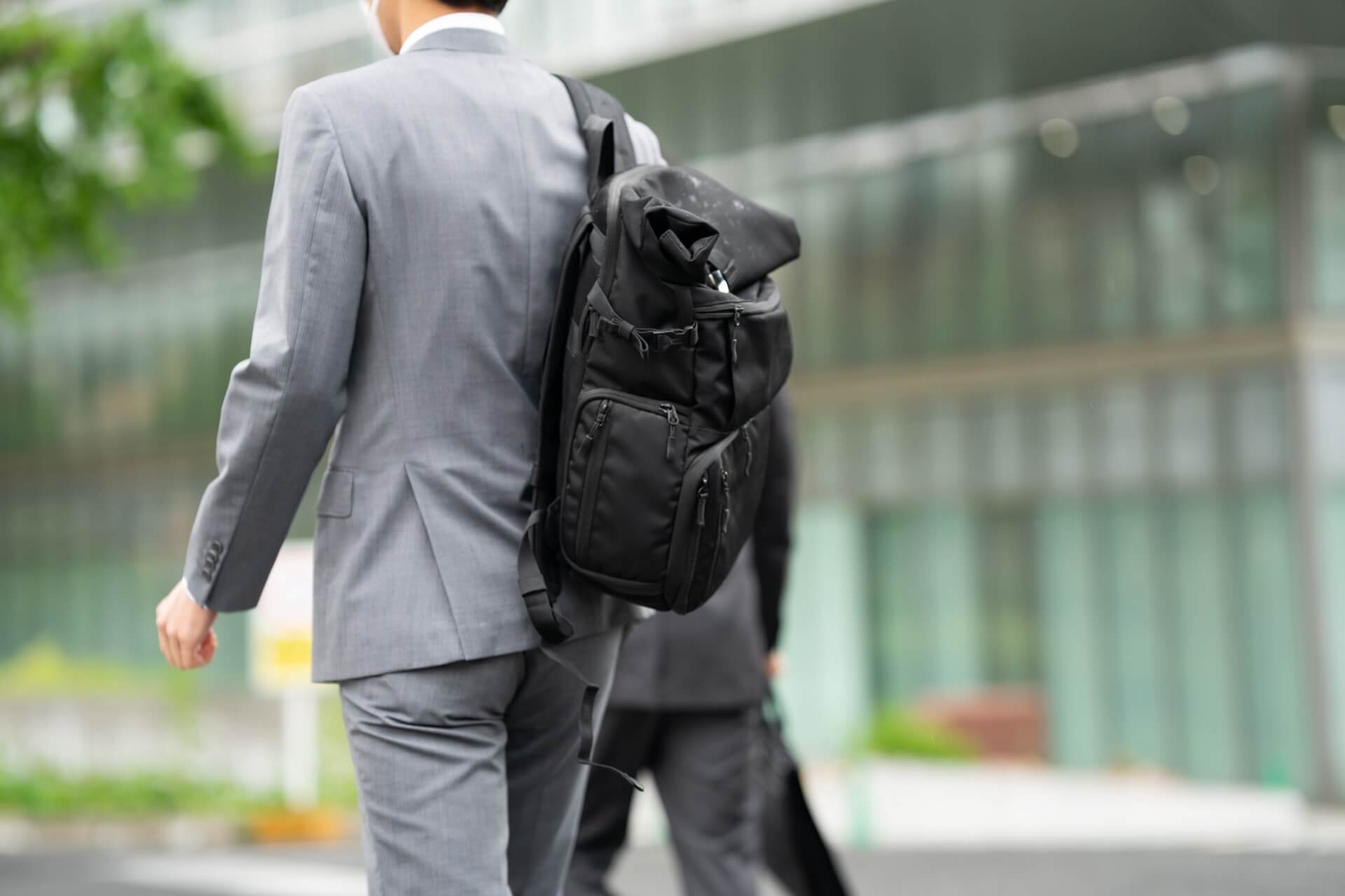 スーツの上から大きなビジネスリュックを背負って歩く男性