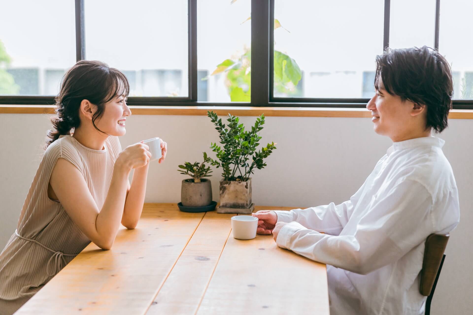 明るいカフェのテーブルで向かい合って会話する男女