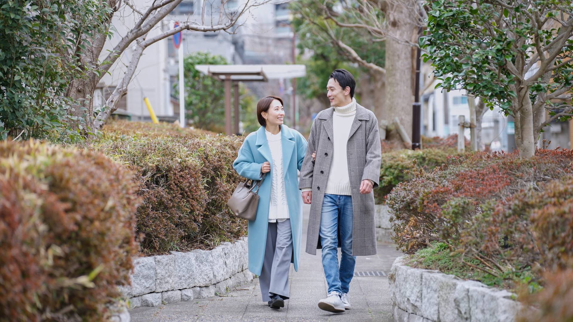 秋の並木道をコート姿で並んで歩く男女