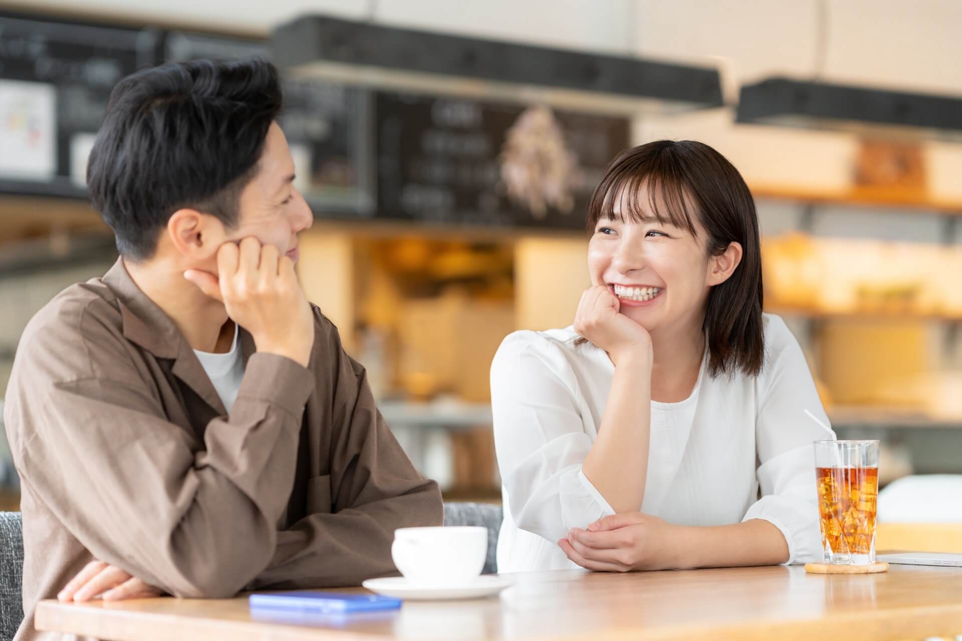 カフェのカウンターで頬づえをつきながら会話を楽しむ男女