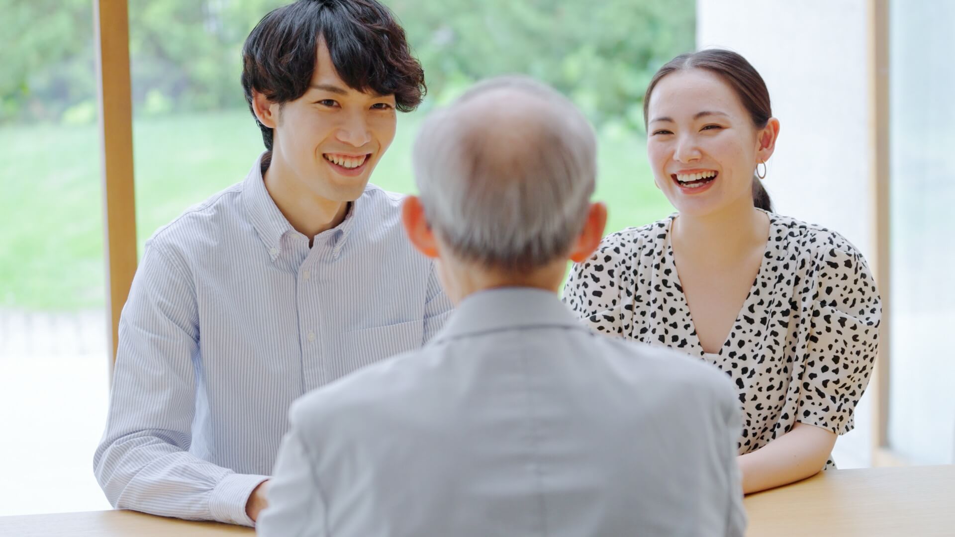 年配の男性と向かい合い、笑顔で話す若い男女