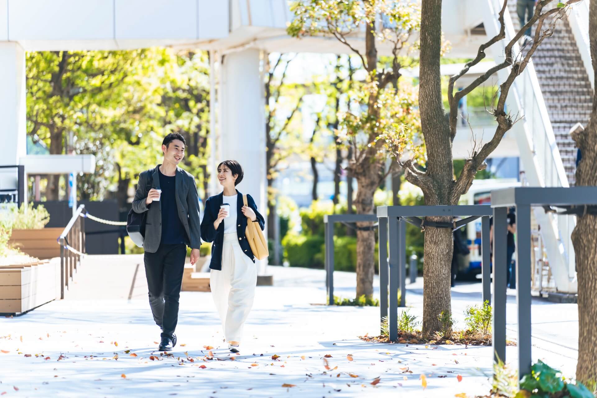 秋の並木道を並んで歩く男女