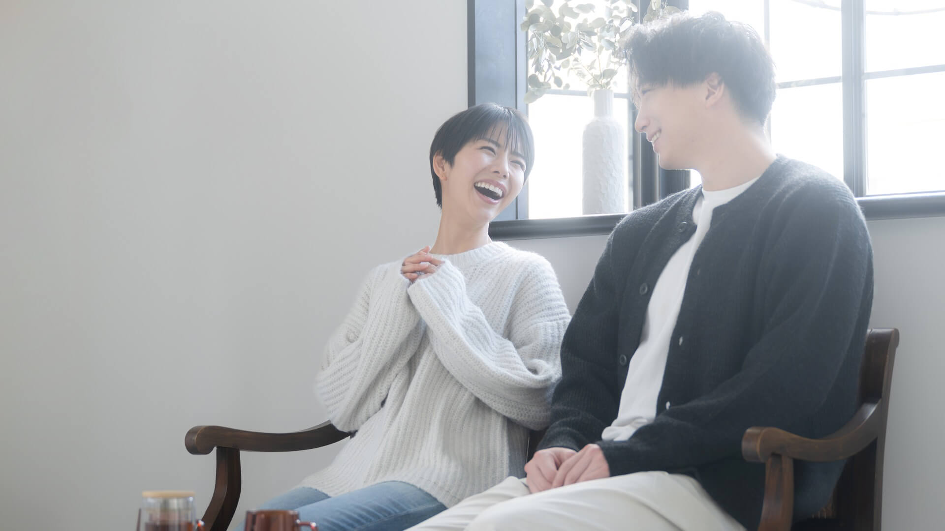 窓辺の明るい部屋で楽しそうに笑い合う男女