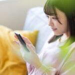 ソファでスマートフォンを操作する女性
