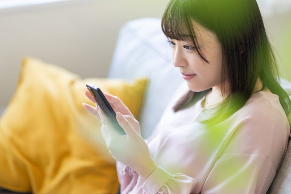 ソファでスマートフォンを操作する女性