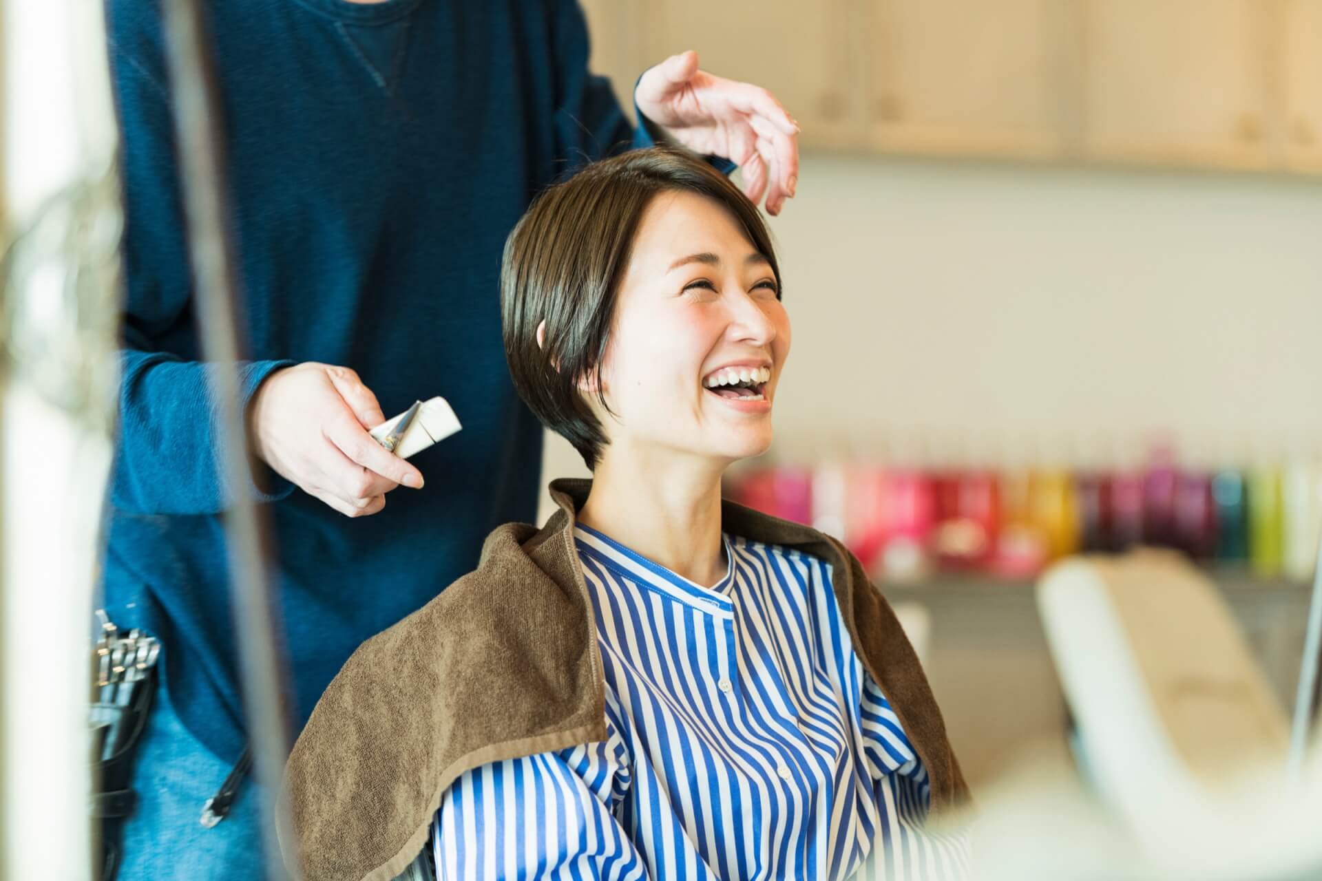 美容室でヘアカットを受けて笑顔を見せる女性