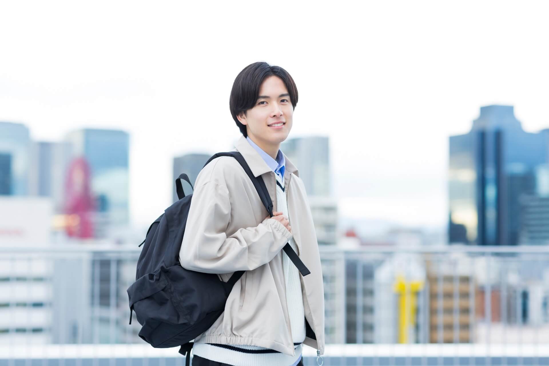 黒いリュックを背負って街に立つ日本人男性