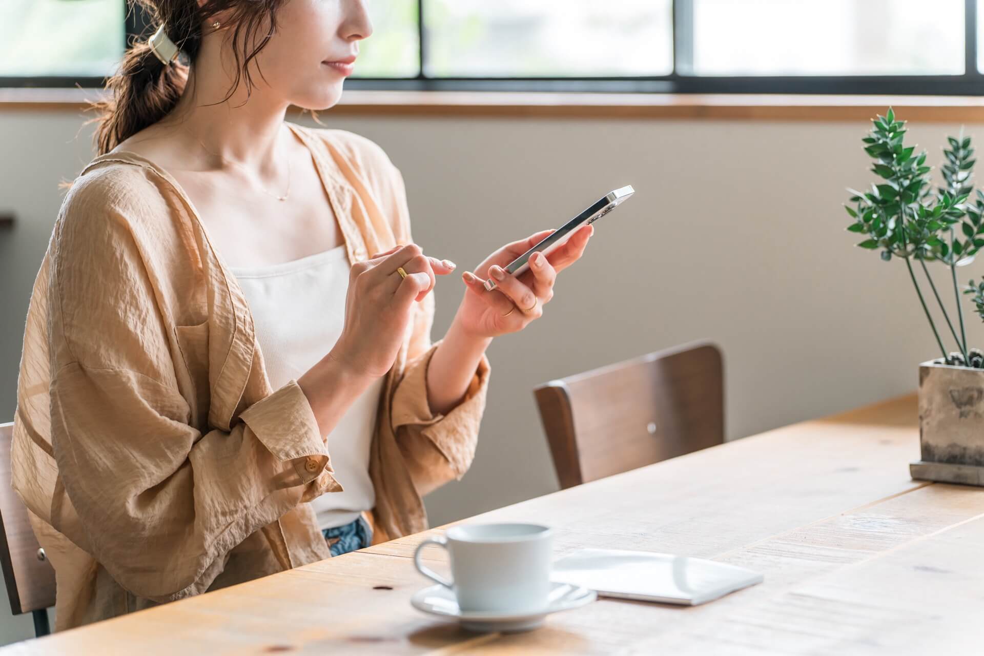 カフェのテーブルでスマートフォンのメッセージを確認する女性