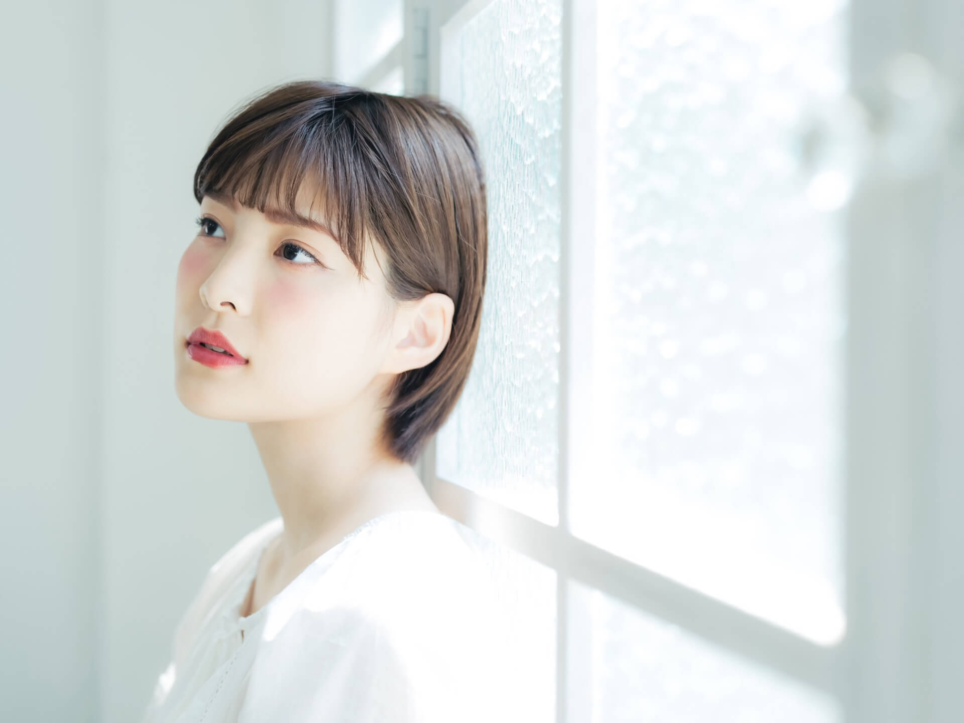 窓から入るやわらかな自然光の中で撮影された女性のポートレート