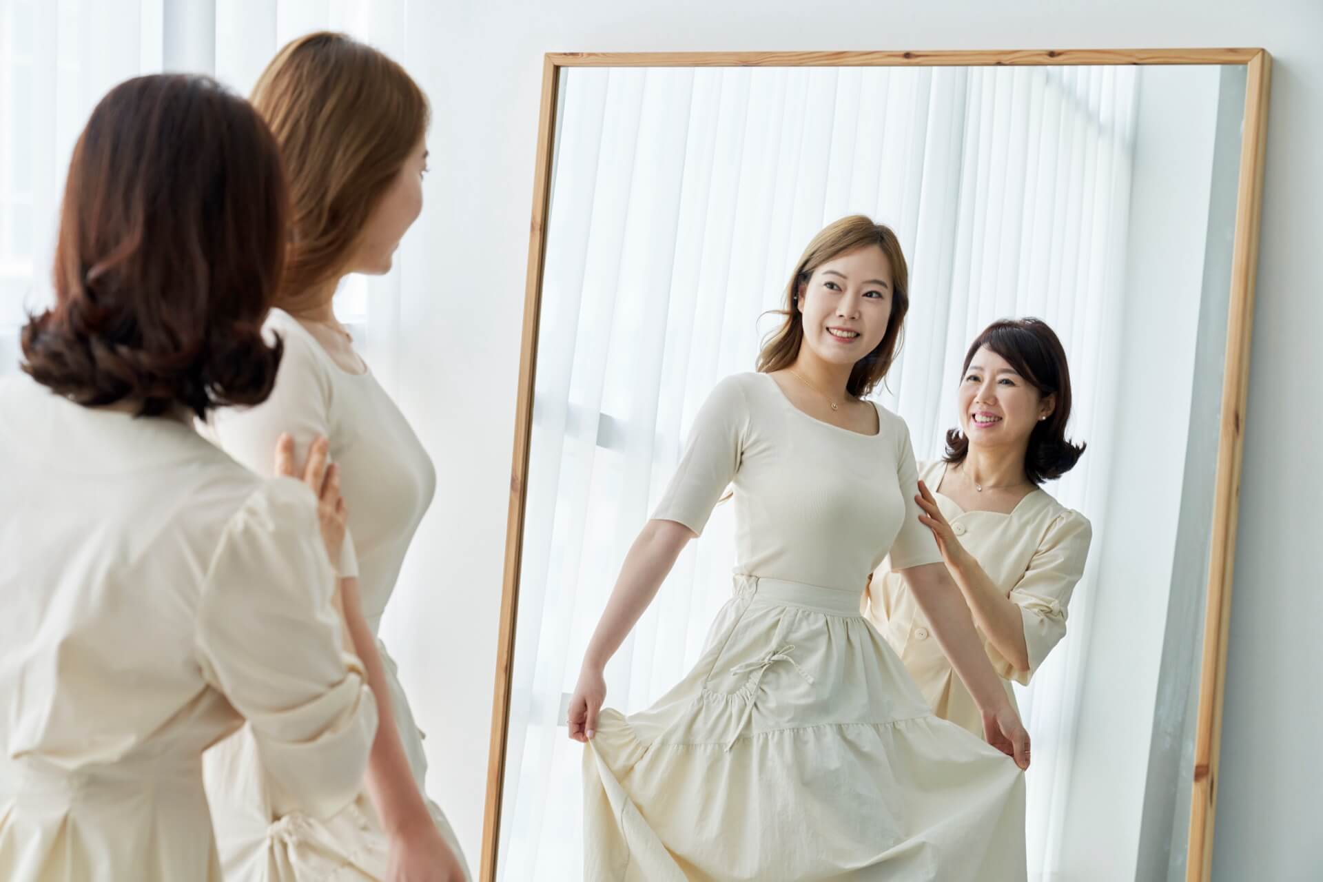 全身鏡の前でアイボリーのワンピースを試着する女性