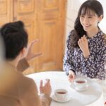 カフェのテーブルで紅茶を前に笑顔で話す婚活中の男女