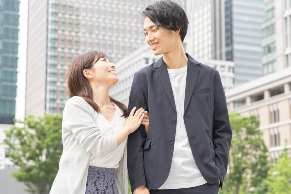 オフィス街で寄り添って笑顔を交わすジャケット姿の男性と女性