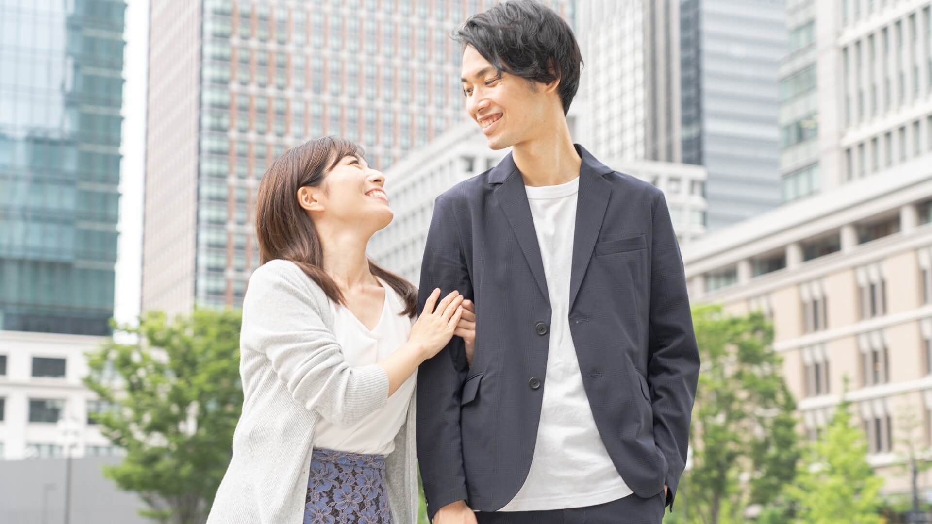 オフィス街で寄り添って笑顔を交わすジャケット姿の男性と女性