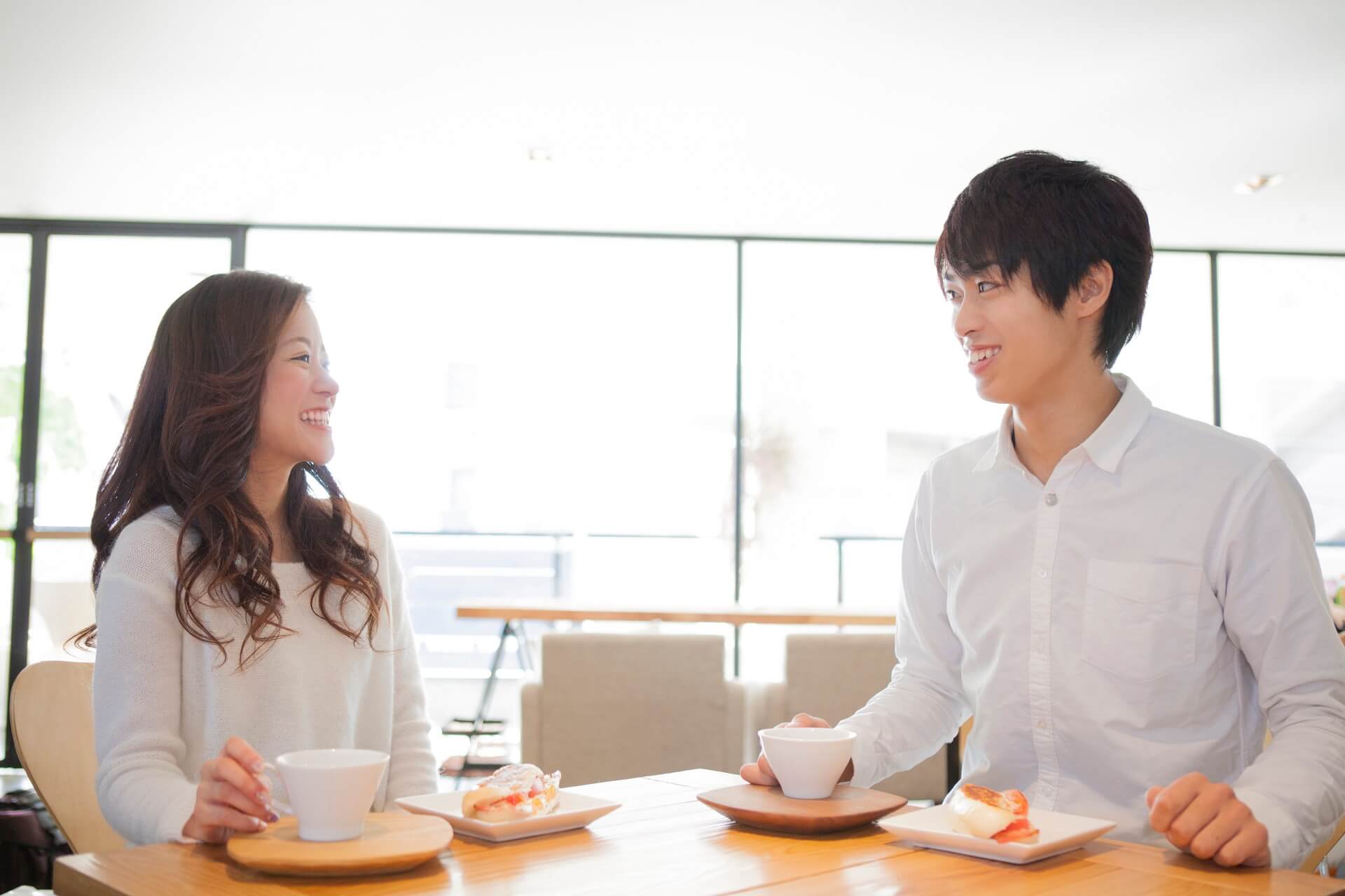 カフェで向かい合って会話する白シャツの男性と女性