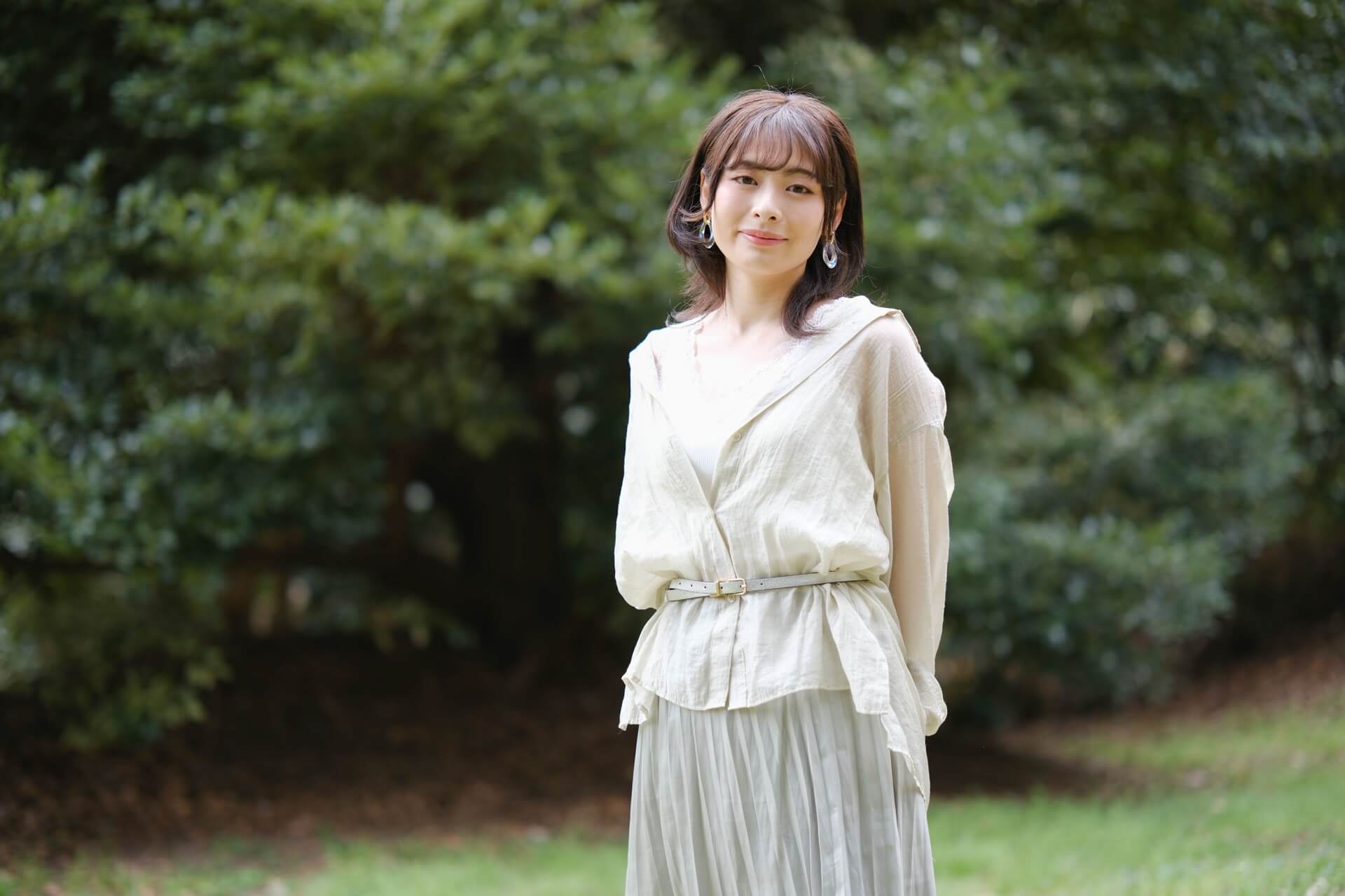 柔らかなブラウスをウエストマークし、プリーツスカートを合わせた女性