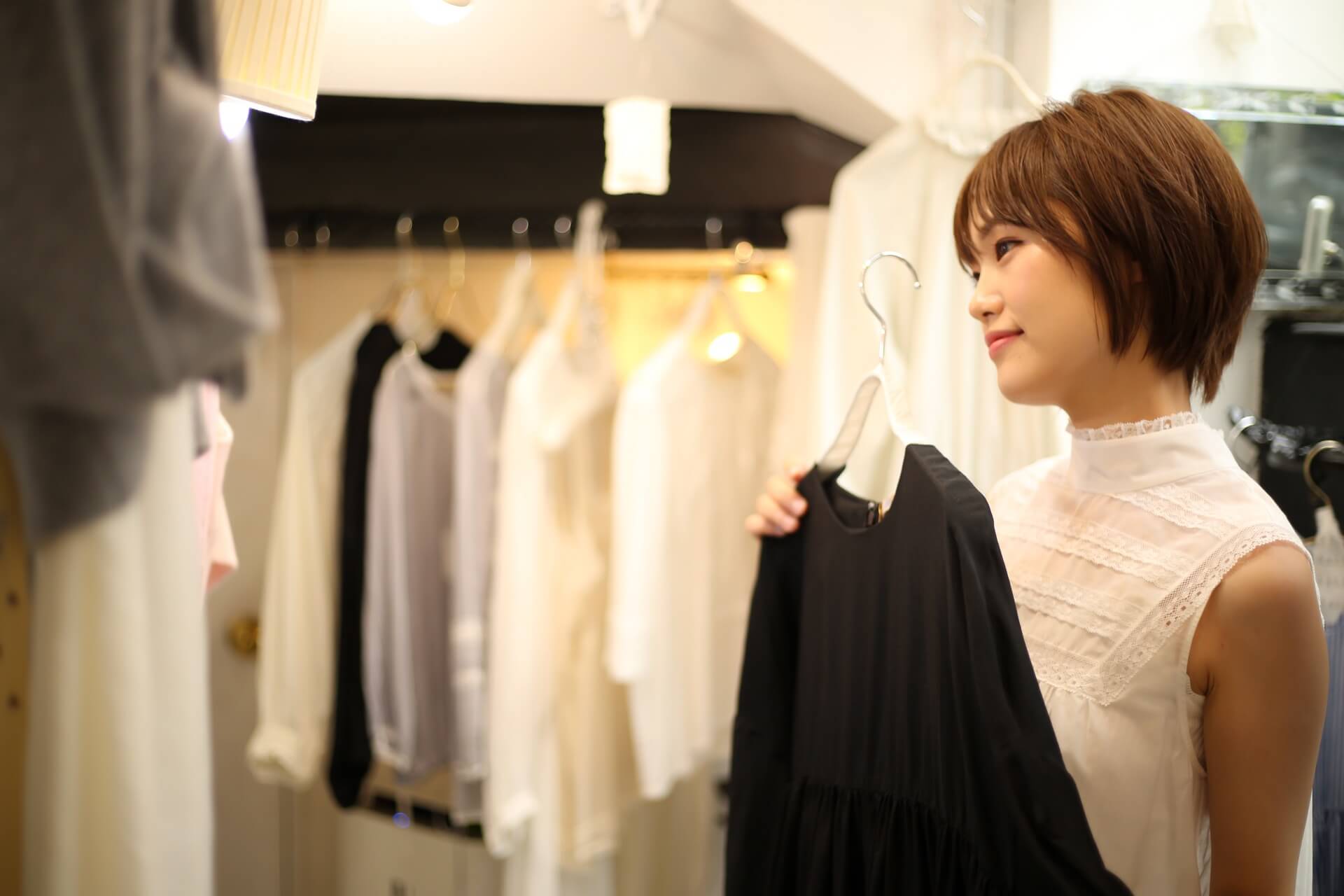 ショップで黒い服を手に取り鏡の前で見比べる女性