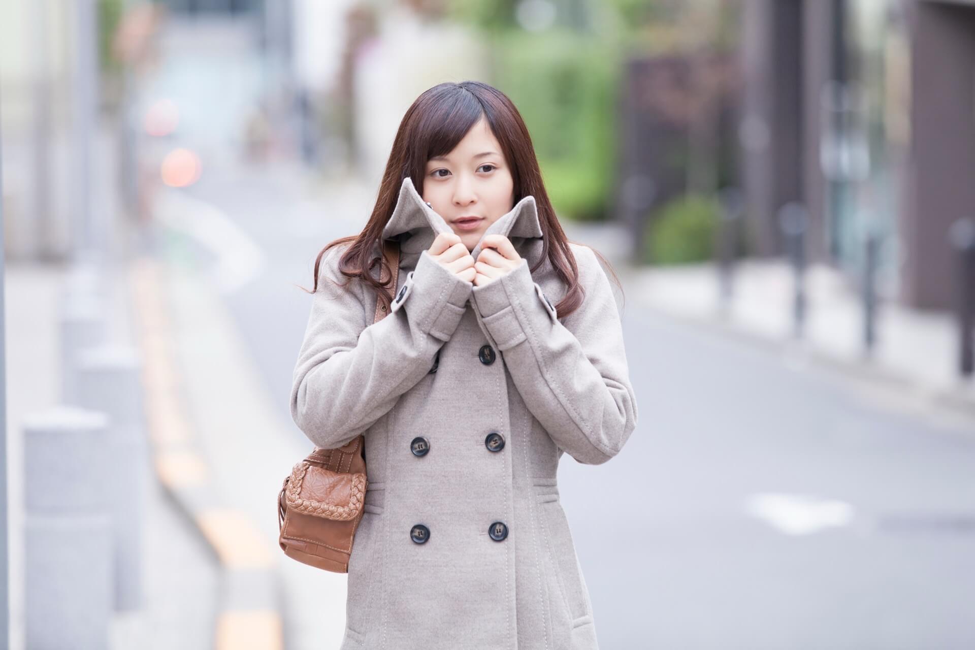 ライトグレーのウールコートを着て、街に立つ女性