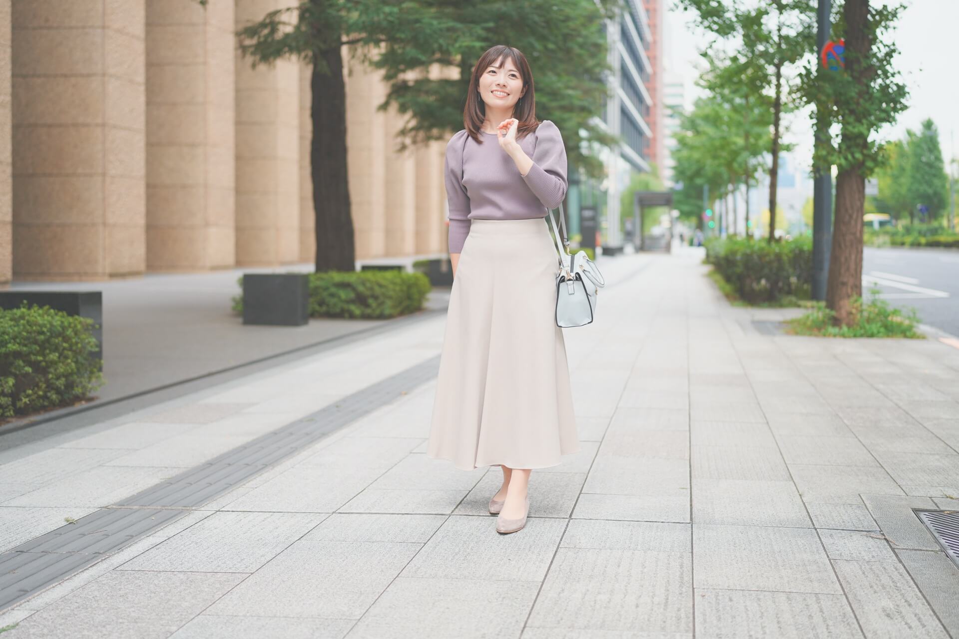 ゆったりしたニットにロングスカートを合わせて街を歩く女性