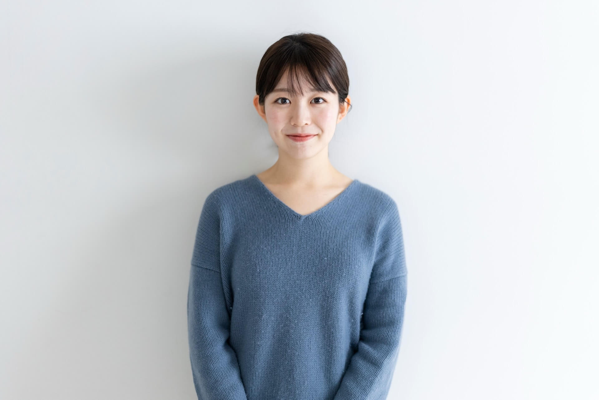 シンプルなブルーのVネックニットを着た女性